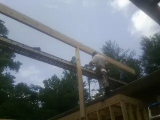 Carpenter setting a ridge beam over a new addition frame — Ice Dam Removal by Roofing Brothers in Poteet