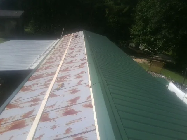 Old rusted panels beside newly installed green metal roofing — Wind Damage Roof Repair by Roofing Brothers in Poteet