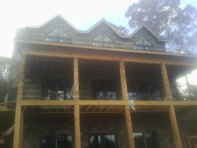 Dormers and porch framing on a large log home under construction — Roof Coating work by our crew in Poteet