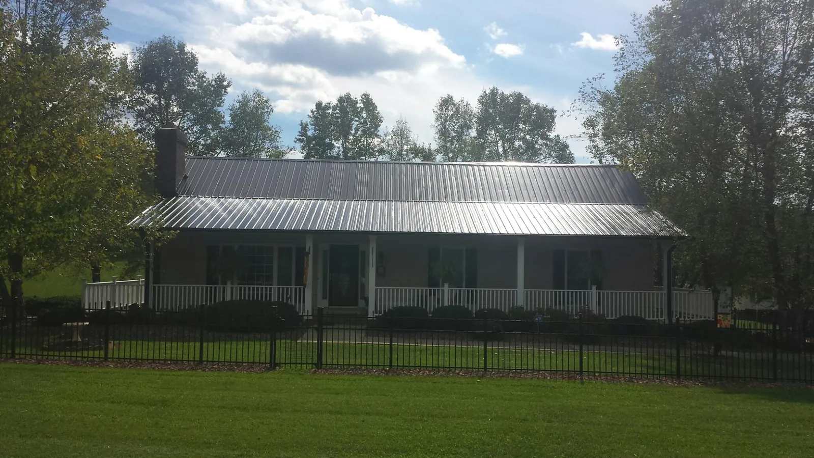 Gray metal roof on a brick ranch with a full width front porch — Gutter Guard Installation work by our crew in Poteet