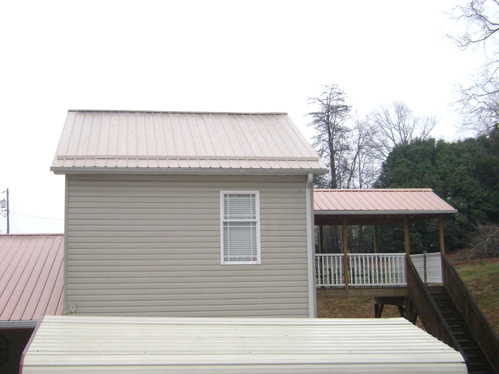 Tan metal roofs on a two story addition and attached porch, from a Roof Replacement job in Poteet