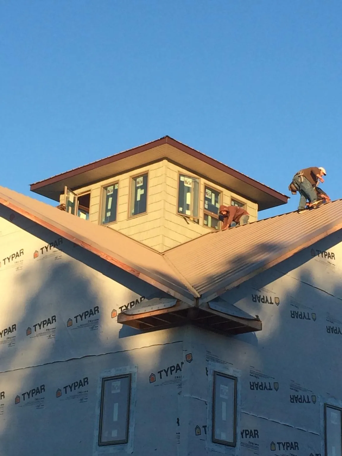 Roofers working around a rooftop cupola on a new metal roof at sunset — Roof Waterproofing in Poteet by Roofing Brothers
